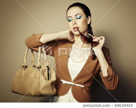 Portrait of beautiful young woman with a leather bag 89620483