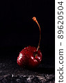 one red cherry with water drops on a black stone background 89620504