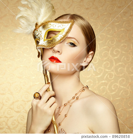 Beautiful young woman in mysterious golden Venetian mask 89620858