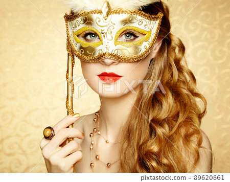 Beautiful young woman in mysterious golden Venetian mask 89620861
