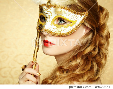 Beautiful young woman in mysterious golden Venetian mask 89620864