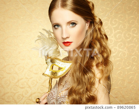 Beautiful young woman in mysterious golden Venetian mask 89620865