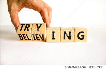 Trying and believing symbol. Businessman turns wooden cubes and changes the word Believing to Trying. Beautiful white table white background, copy space. Business, trying and believing concept. 89622993