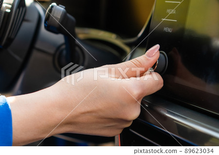 Close up woman in blue blazer change the volume on the infotainment sitting in the car. Close up woman in blue blazer change the volume on the infotainment sitting in the car. 89623034