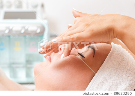 Cosmetologist makes a woman a procedure of facial acupressure. Close-up of the client's face. Concept of cosmetology and treatment Cosmetologist makes a woman a procedure of facial acupressure. Close-up of the client's face. Concept of cosmetology and treatment 89623290