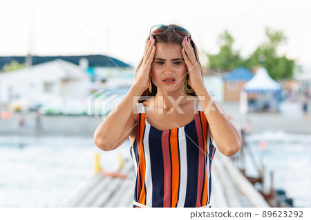 Stress. The elegant woman holds her head in her hands, in pain. Outdoor. Concept of negative emotions and pain Stress. The elegant woman holds her head in her hands, in pain. Outdoor. Concept of negative emotions and pain 89623292