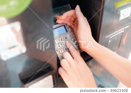 ATM and banking operations. The woman covered with her hand, drives a pin from a Bank card in the machine ATM and banking operations. The woman covered with her hand, drives a pin from a Bank card in the machine 89623308