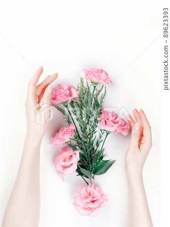 Delicate female hands frame the scattered pink buds of eustoma. White background. Flat lay. The skin is albino. Copy space. The concept of Floristics and tenderness Delicate female hands frame the scattered pink buds of eustoma. White background. Flat lay. The skin is albino. Copy space. The concept of Floristics and tenderness 89623393