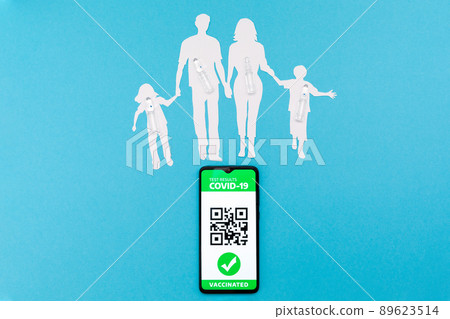 Cellphone with app of digital immunity passport and a silhouette of a family cutted out of paper, with vaccines on a blue background. Flat lay. The concept of vaccination and new normal Cellphone with app of digital immunity passport and a silhouette of a family cutted out of paper, with vaccines on a blue background. Flat lay. The concept of vaccination and new normal 89623514