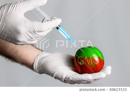 Man in gloves makes medical injection chemical in peach fruit, which changes color. The concept of GMO products, vegetables and fruits 89623533