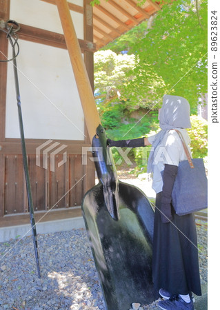 A worshiper looking at a large shovel and fire chopsticks (Kasuisai Kannon-do, Fukuroi City, Shizuoka Prefecture) 89623824
