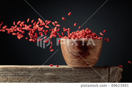 Dried goji berries are poured into a wooden bowl. 89623891