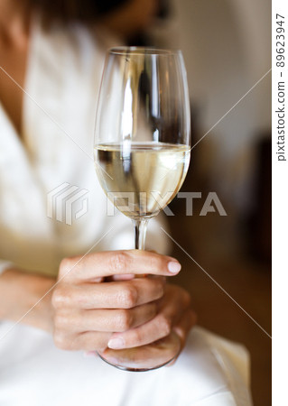 Bride in bathrobe holding wineglass Bride in bathrobe holding wineglass 89623947