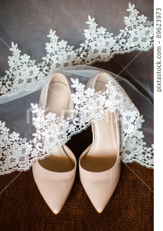 Wedding shoes and veil on the brown background 89623973