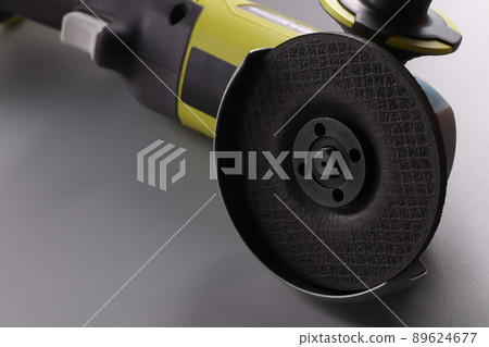 Electrical saw, grinder with nozzle on grey surface, detailed picture of powerful circular saw tool 89624677