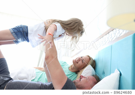 Father throws kid in air and play, family chill in bed, happy and healthy relationship in family Father throws kid in air and play, family chill in bed, happy and healthy relationship in family 89624680
