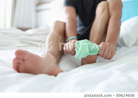 Man try to pull sock on foot, dress up to go out, sit on bed for comfort Man try to pull sock on foot, dress up to go out, sit on bed for comfort 89624686