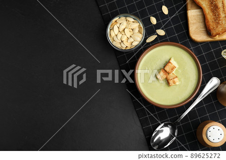 Delicious broccoli cream soup with croutons served on black table, flat lay. Space for text 89625272