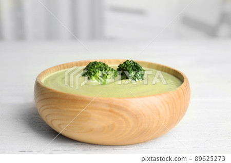 Delicious broccoli cream soup served on white wooden table 89625273