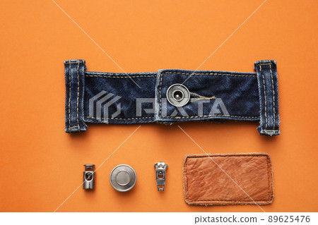Flat lay composition with garment accessories and cutting details for jeans on orange background 89625476