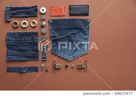 Flat lay composition with garment accessories and cutting details for jeans on brown background Flat lay composition with garment accessories and cutting details for jeans on brown background 89625477