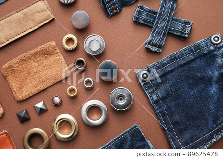 Flat lay composition with garment accessories and cutting details for jeans on brown background Flat lay composition with garment accessories and cutting details for jeans on brown background 89625478