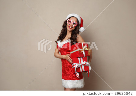 Beautiful woman in Christmas costume with gift boxes on beige background 89625842