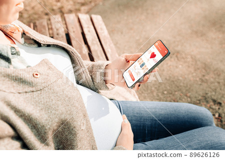 Pregnancy calendar app. Mobile pregnancy online maternity application. Pregnant mother using phone. Concept of pregnancy, maternity, expectation for baby birth. Pregnancy calendar app. Mobile pregnancy online maternity application. Pregnant mother using phone. Concept of pregnancy, maternity, expectation for baby birth. 89626126