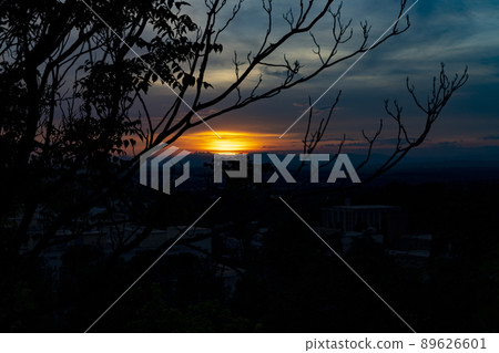 Sunset. Sunset with high clouds leaving the sky orange and blue. Backlight of the leaves and branches of the trees in a park in Madrid, in Spain. Europe. Horizontal photography. 89626601