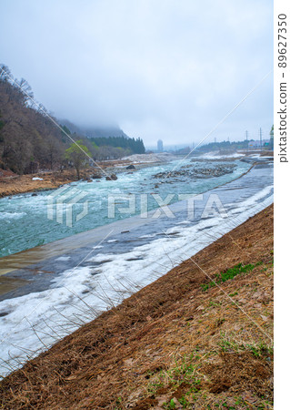Snow-melting Uono River, view of the upstream of Shinbenbashi, near Yuzawa IC on the Kan-Etsu Expressway, remaining snow, early spring scenery 89627350