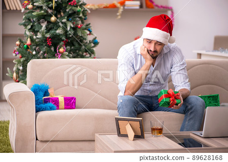 Young man celebrating Christmas at home alone Young man celebrating Christmas at home alone 89628168