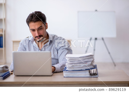Young male employee and too much work in the office 89629119