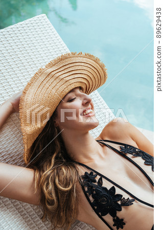 Gleesfully laughing by baring the beautiful teeth of a girl in a hat and swimsuit at the pool in a schizlong close-up 89629438