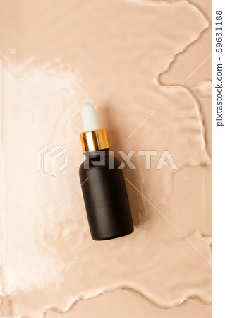 Amber matt glass dropper bottle with black lid in water on beige light background. Skincare products , natural cosmetic. Beauty concept for face and body care 89631188