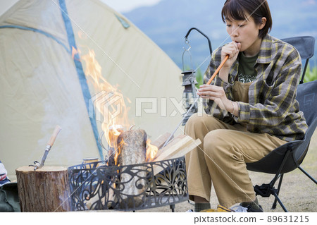 A young woman who uses a fire-breathing stick on a bonfire Solo camp 89631215