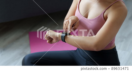 Beautiful sporty woman using smart watch checking notify after sports training at gym with Virtual Reality Modeling Software Application. Beautiful sporty woman using smart watch checking notify after sports training at gym with Virtual Reality Modeling Software Application. 89631471