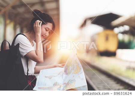 Young traveler woman looking on maps planning trip at train station. Summer and travel lifestyle concept. Young traveler woman looking on maps planning trip at train station. Summer and travel lifestyle concept. 89631624