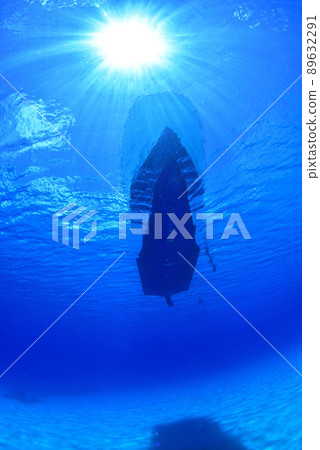 一艘漂浮在無限清澈的大海和燦爛的陽光中的小船 89632291
