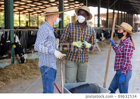 Farmers in protective masks discussing working process near stall 89632534