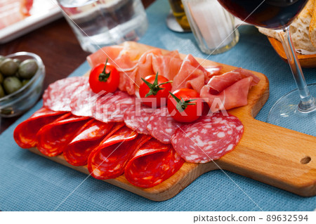 Spanish tapas - slicing sausages and jamon served on wooden board Spanish tapas - slicing sausages and jamon served on wooden board 89632594