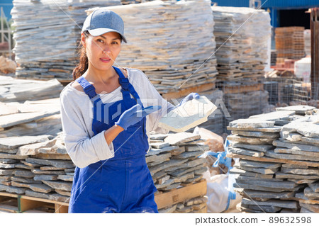 Asian woman worker demonstrates a stone tile in a warehouse Asian woman worker demonstrates a stone tile in a warehouse 89632598
