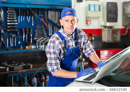 Mechanic man using laptop checking car in workshop Mechanic man using laptop checking car in workshop 89632599