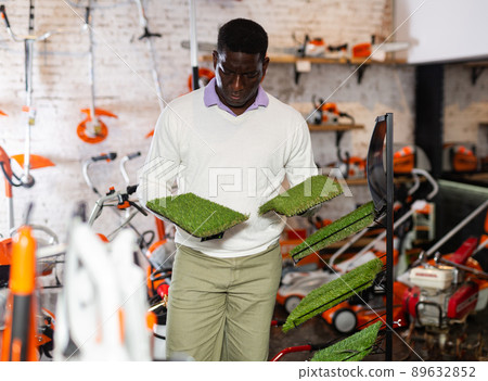 Man deciding on artificial turf from assortment in garden equipment shop Man deciding on artificial turf from assortment in garden equipment shop 89632852