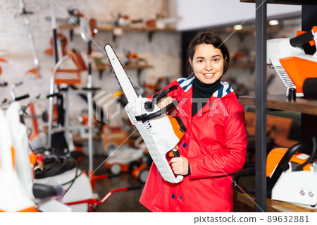 Woman with chainsaw in gardening tools store 89632881