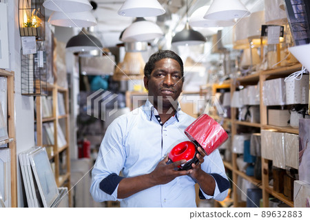 Smiling african american man buying table lamp in store 89632883