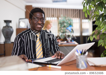 Focused african american man types documentation on a computer in the office 89632886