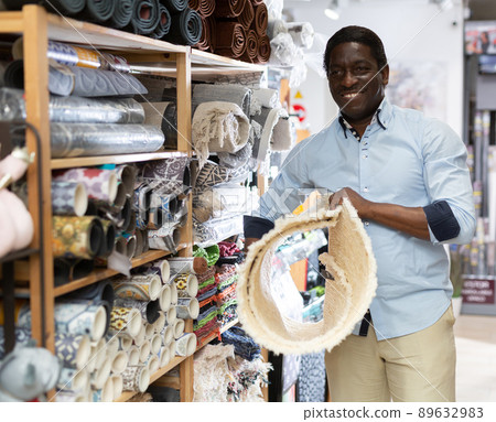 Interested african american man choosing floor mat in store Interested african american man choosing floor mat in store 89632983