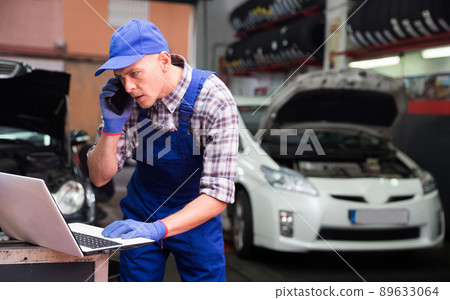 Auto mechanic communicates with client on a smartphone in car service 89633064
