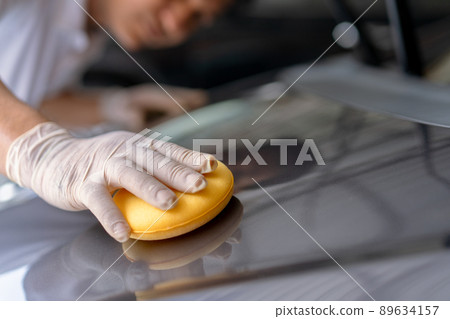 Asian skillful and professional service man polishing and detailing on a car body, professional workman waxing a wax on a vehicle. Car wash service. Asian skillful and professional service man polishing and detailing on a car body, professional workman waxing a wax on a vehicle. Car wash service. 89634157