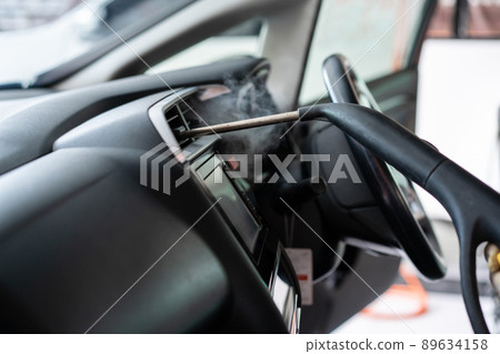 Professional car care service, unrecognizable skillful male worker using a steam machine or heat sterilization inside the car air conditioner system. Steaming a hot air into air conditioner system. 89634158